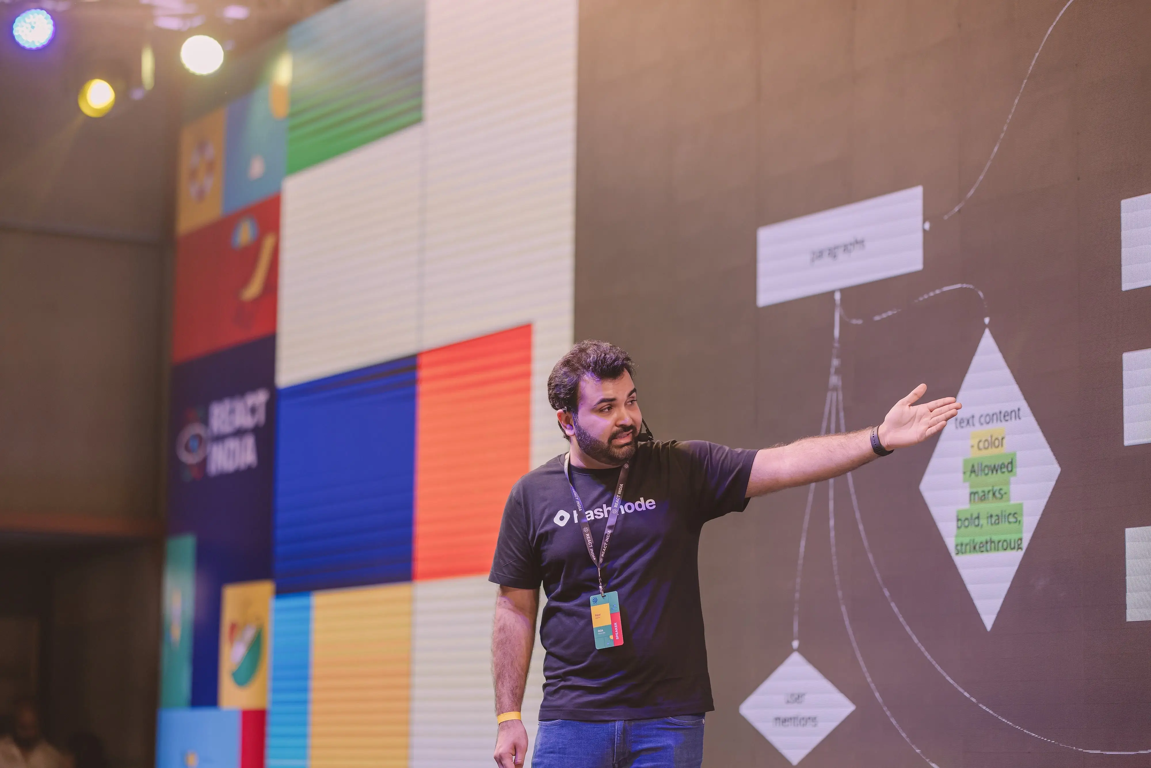 Rajat explaining a diagram on stage at React India